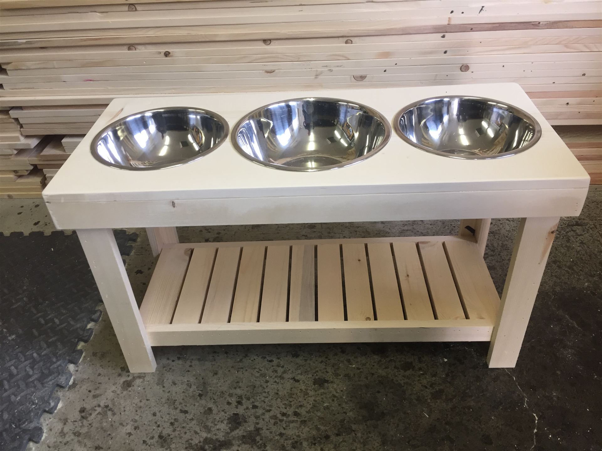 Elevated pine dog bowl stand with three stainless bowls and a slatted lower shelf