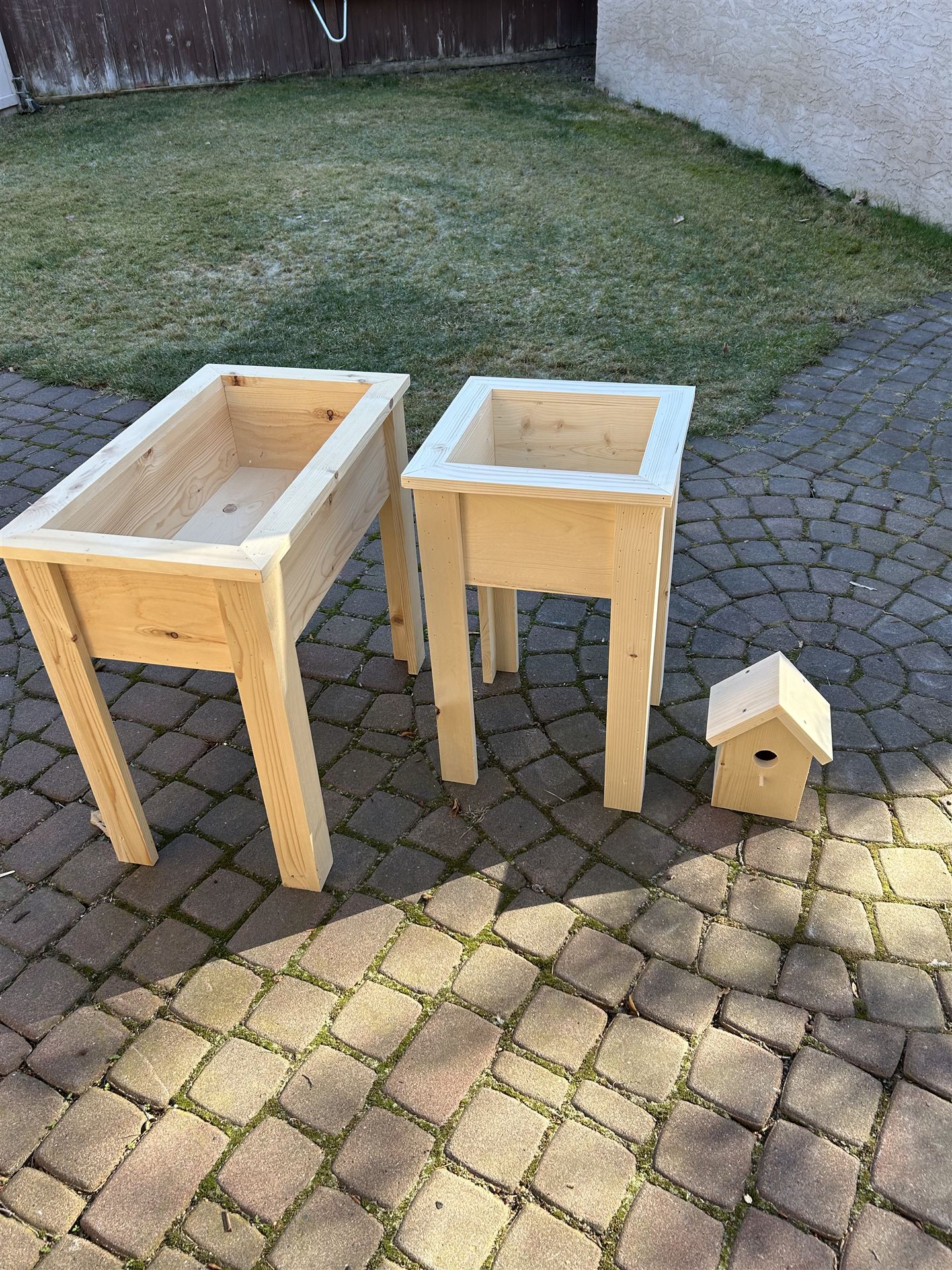 Raised pine planter boxes staged outdoors alongside a birdhouse